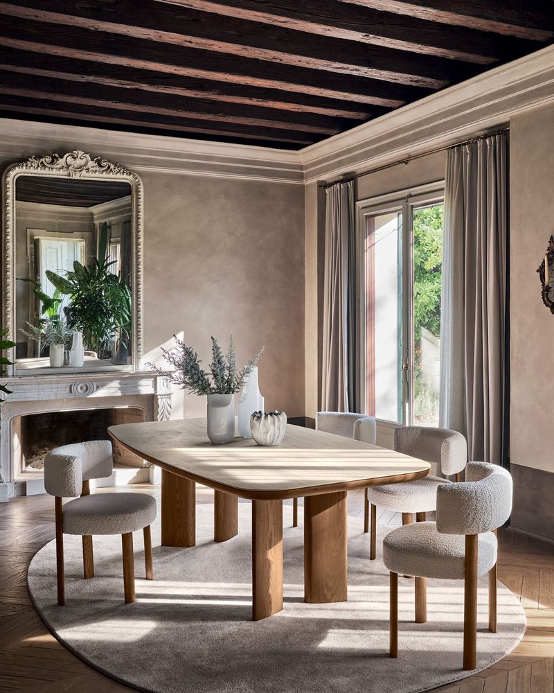 Salle à manger avec poutres apparentes, grande table en bois et chaises bouclées, Calligaris
